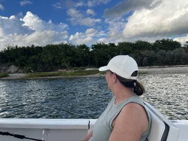 A woman enjoys the scenic view from a boat, surrounded by lush greenery and a serene waterway — a perfect moment for relaxation and exploration.