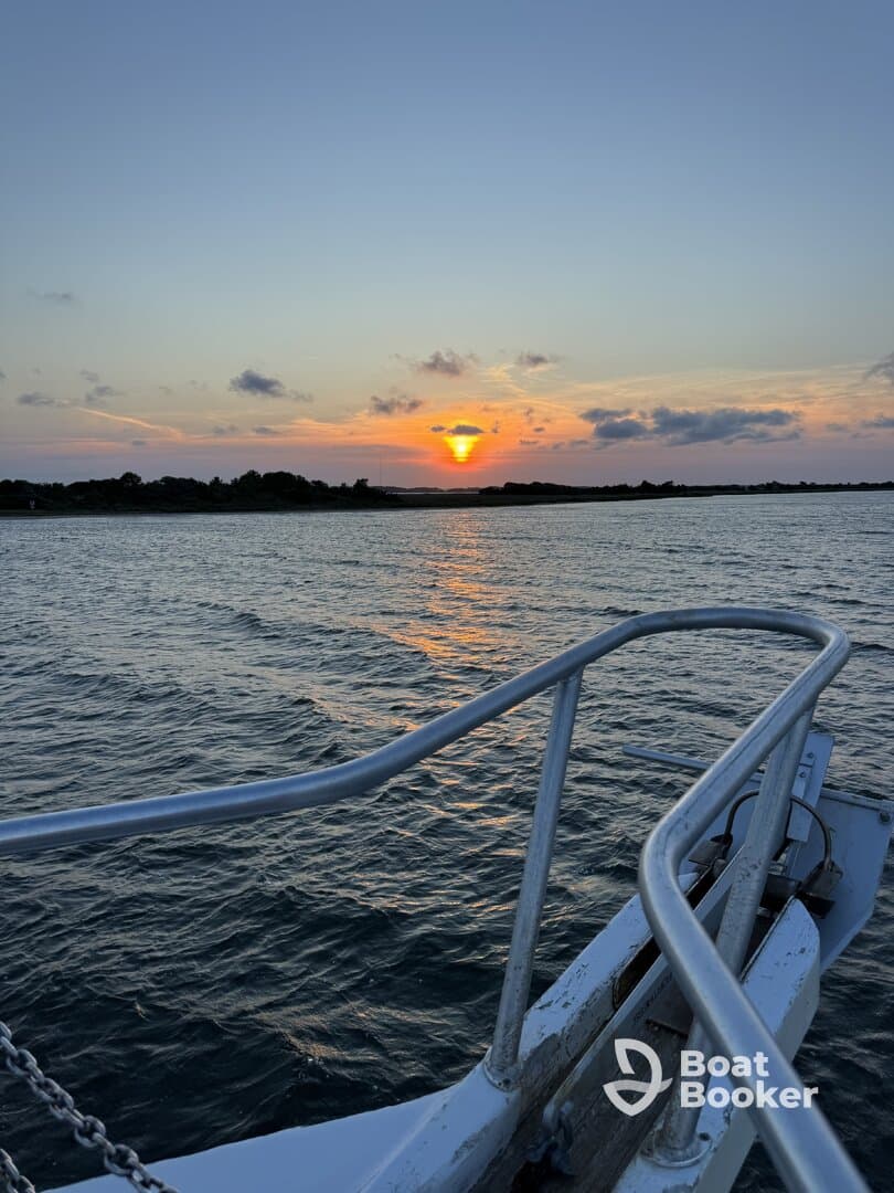 A serene sunset view from the bow of a boat, showcasing the tranquil waters and vibrant colors of the evening sky — perfect for romantic evening cruises.