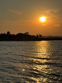 A stunning sunset casts golden reflections on the water, creating a picturesque scene perfect for evening boat cruises.