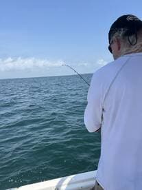 A fisherman casts his line into the open water, enjoying a day of fishing on the boat — a perfect way to experience the thrill of the catch.