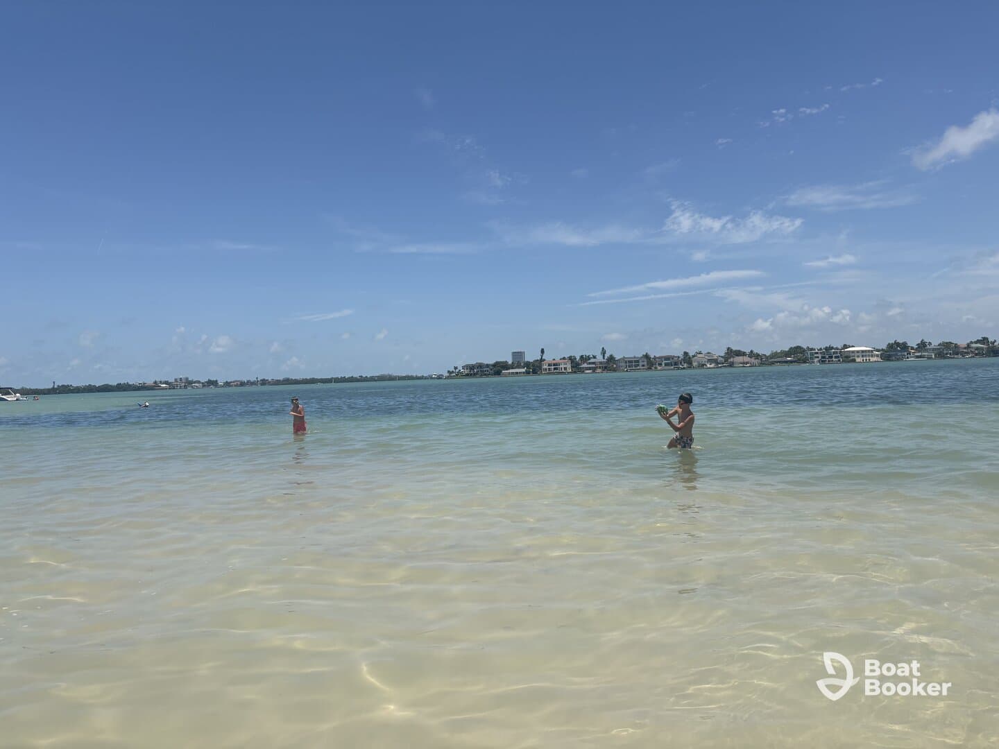 Two individuals enjoy a sunny day at the beach, wading in the shallow waters — a perfect setting for family fun and relaxation.