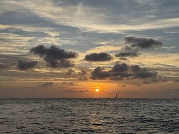 A stunning sunset over the ocean, with vibrant colors reflecting on the water — a perfect backdrop for evening boat cruises or romantic getaways.