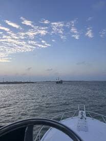 A scenic view from the bow of a boat, showcasing a distant ship against a beautiful sky — perfect for maritime adventures and sightseeing.