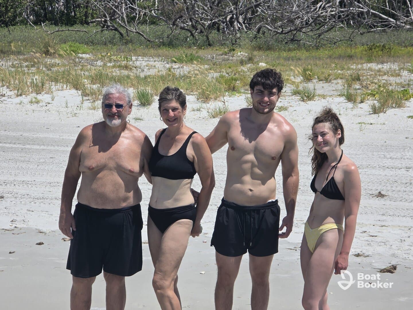 A cheerful family poses together on the beach, enjoying a sunny day by the water — perfect for creating lasting memories during summer vacations.
