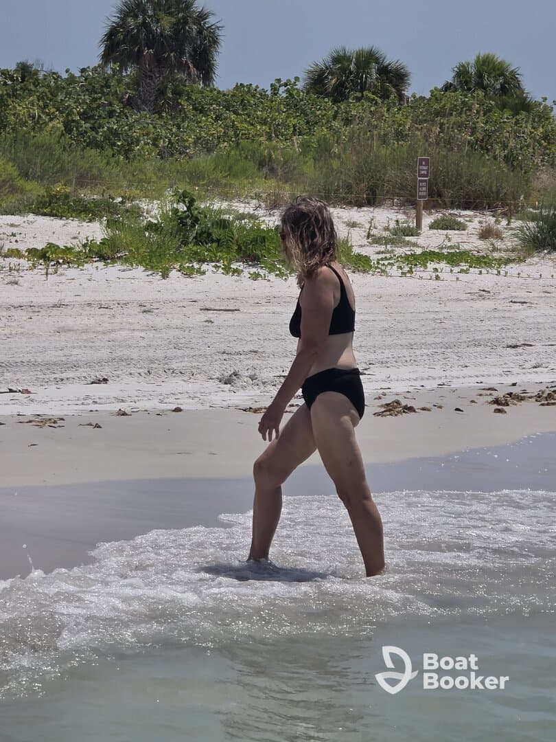 A woman enjoys a sunny day at the beach, wading through the gentle waves — a perfect scene for summer relaxation and fun in the sun.