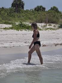 A woman enjoys a sunny day at the beach, wading through the gentle waves — a perfect scene for summer relaxation and fun in the sun.