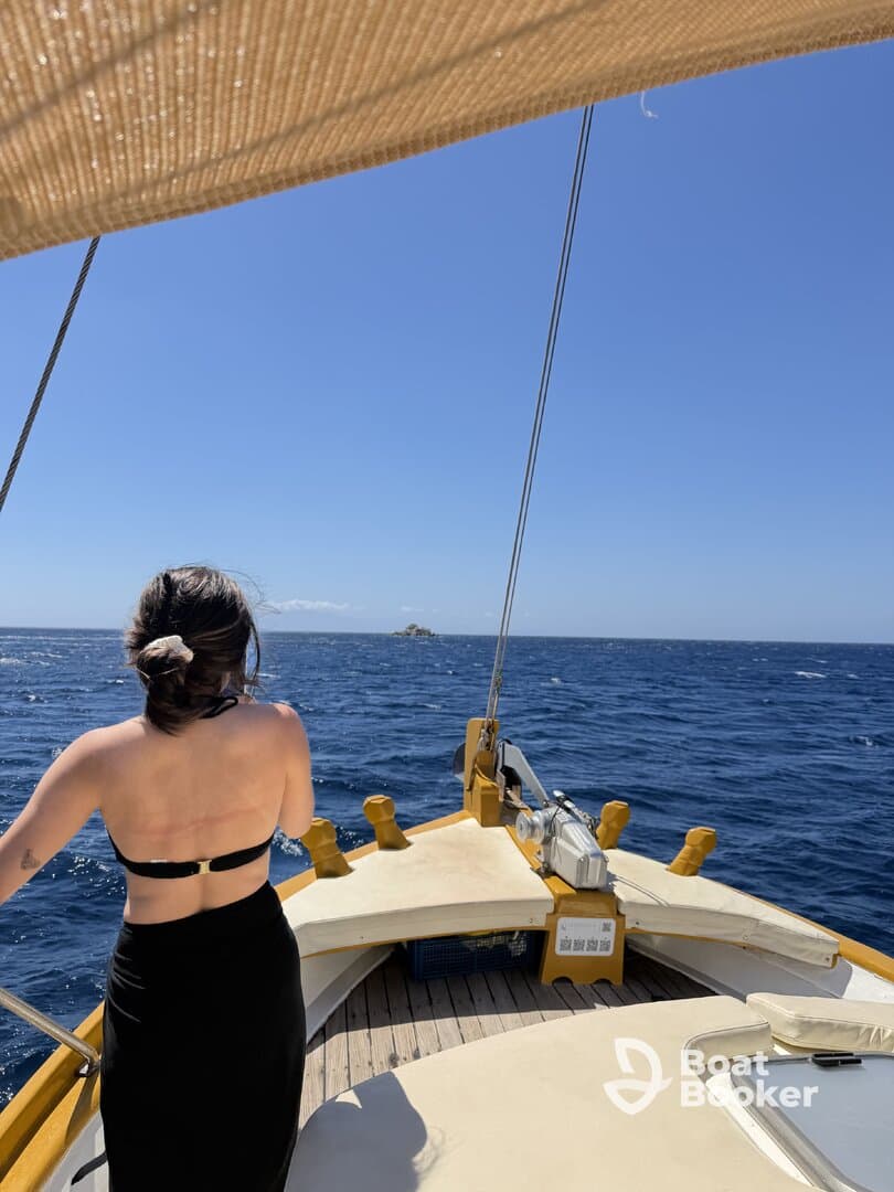 A woman enjoys the stunning ocean view from the deck of a sailboat, capturing the essence of a perfect day on the water.