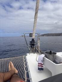 A relaxing moment on the deck of a catamaran, showcasing the lounge area with a view of the ocean — perfect for enjoying drinks and the sea breeze.
