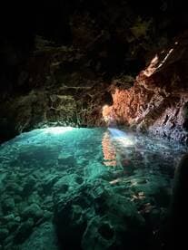 A stunning view of a cave with crystal-clear water reflecting light, showcasing the natural beauty of underwater landscapes — perfect for eco tours and exploration.