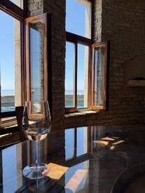 A serene view from inside a boat cabin featuring a glass of wine and large windows showcasing the ocean view — perfect for relaxing moments on the water.