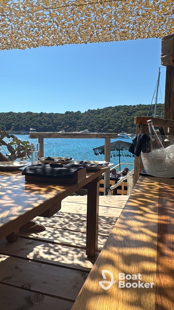 A picturesque view from an outdoor dining area overlooking the serene waters and lush greenery, perfect for enjoying a meal by the beach.