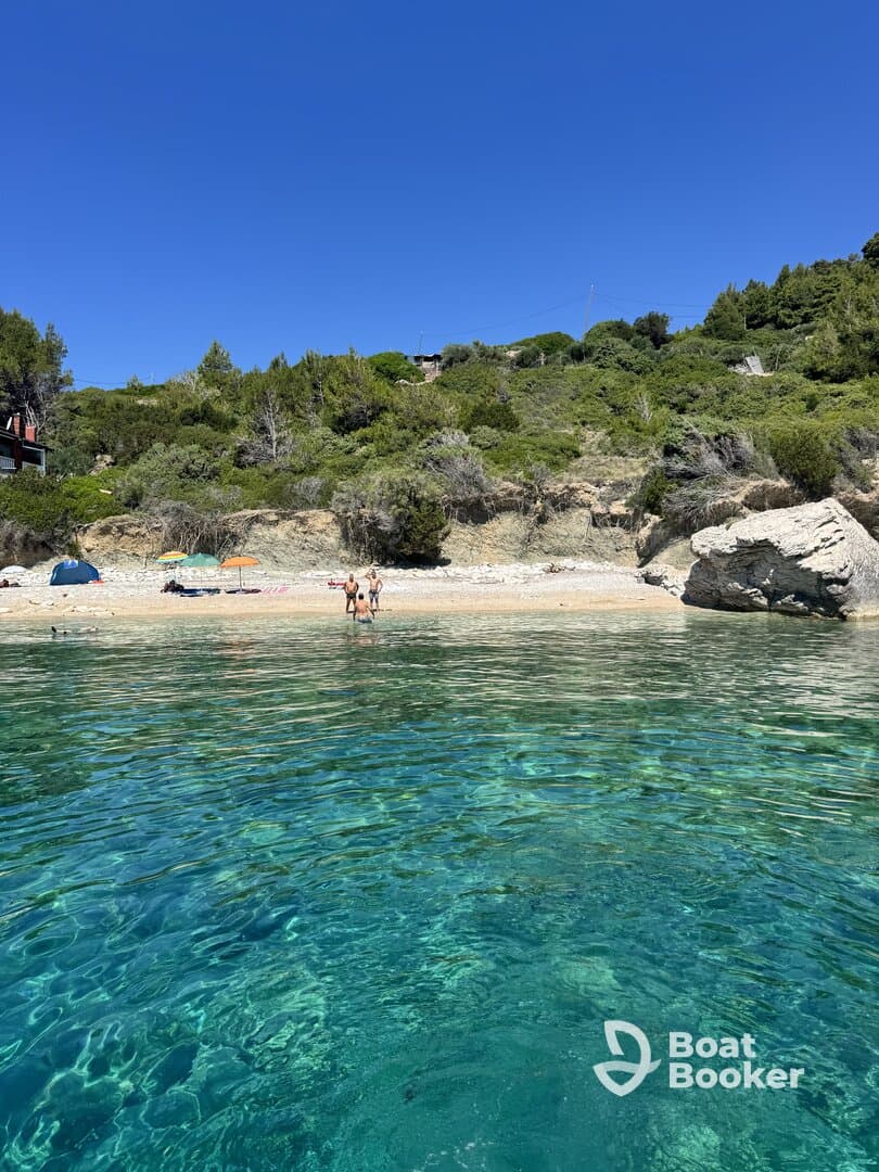 A beautiful beach scene featuring a group of people enjoying the clear waters and sandy shore, perfect for a day of relaxation and fun in the sun.