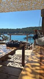A picturesque view from an outdoor dining area overlooking the serene waters and lush greenery, perfect for enjoying a meal by the beach.