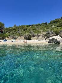 A beautiful beach scene featuring a group of people enjoying the clear waters and sandy shore, perfect for a day of relaxation and fun in the sun.