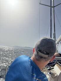A man enjoys the serene view from a sailboat, capturing the essence of a relaxing day on the water.