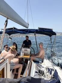 A lively group enjoys a sailing experience on a sunny day, with friends gathered on deck, creating unforgettable memories on the water.