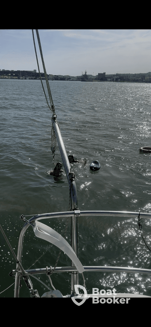 Two individuals enjoy a refreshing swim in the water, with a boat visible in the foreground — a perfect scene for summer fun on the water.
