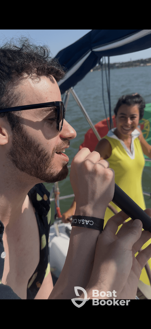 A lively moment on a boat as friends enjoy a fun celebration, with one person singing into a microphone while another smiles in the background — perfect for unforgettable boat party experiences.