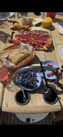 A beautifully arranged charcuterie spread featuring bread, cheeses, and fresh berries, perfect for enjoying on a boat trip.