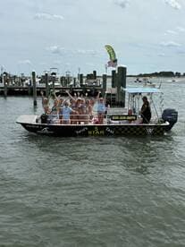 A lively group of friends celebrates aboard a boat taxi, waving enthusiastically as they enjoy their day on the water — perfect for group outings and fun adventures.