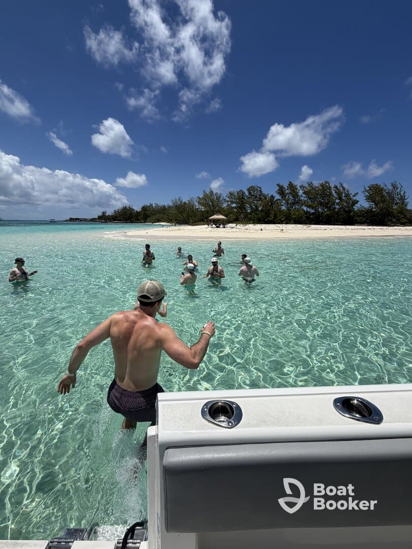 A group of friends enjoys a fun day at the beach, splashing in the clear waters while one person jumps in from the boat — perfect for a memorable day on the water.