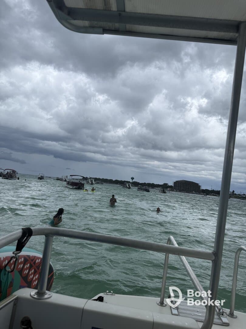 Guests enjoy a fun day swimming in the water near a pontoon boat, surrounded by a lively beach atmosphere — perfect for summer adventures.