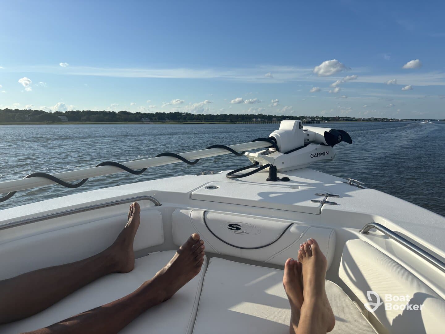 Two pairs of feet relax on the deck of a boat, enjoying a sunny day on the water — a perfect moment for unwinding and soaking in the views.