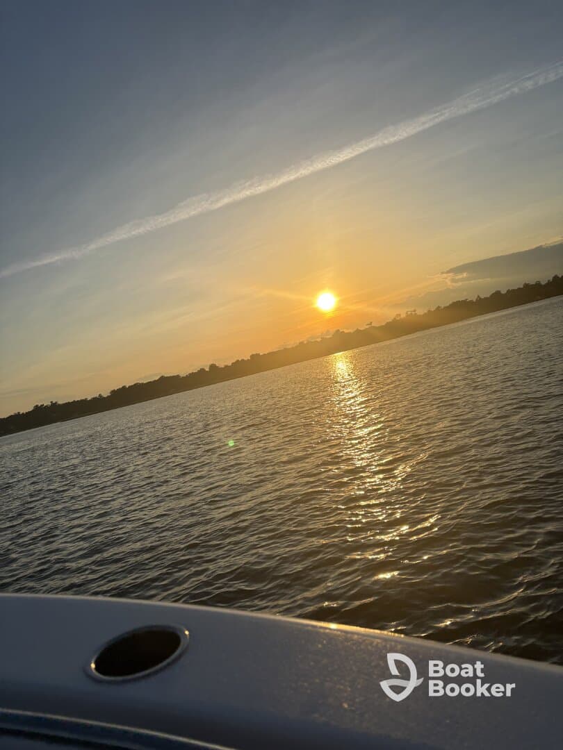 A serene sunset view over the water, captured from the edge of a boat, creating a picturesque scene perfect for evening cruises.