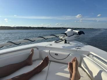 Two pairs of feet relax on the deck of a boat, enjoying a sunny day on the water — a perfect moment for unwinding and soaking in the views.