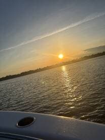A serene sunset view over the water, captured from the edge of a boat, creating a picturesque scene perfect for evening cruises.