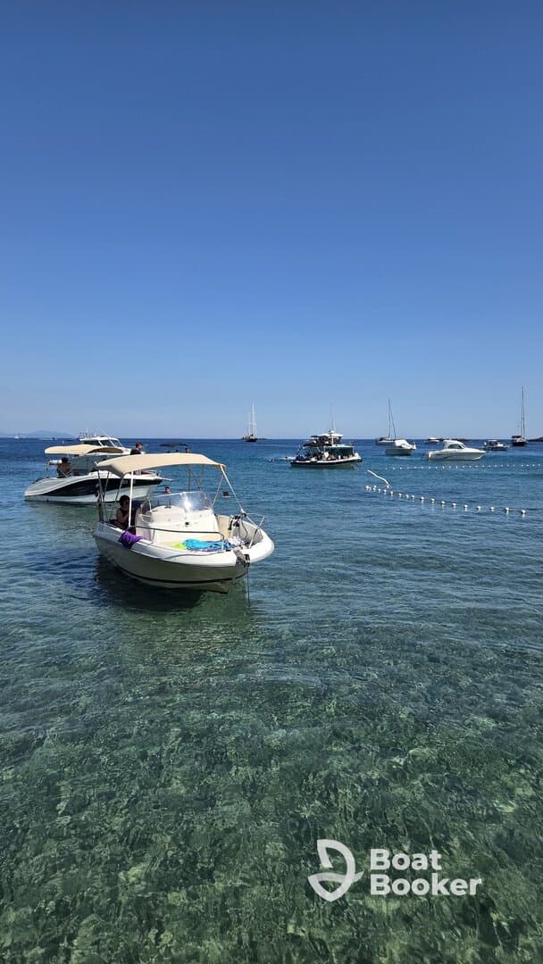 A scenic view of boats anchored in crystal-clear waters, with guests enjoying their time on the water — perfect for a day of relaxation and exploration.
