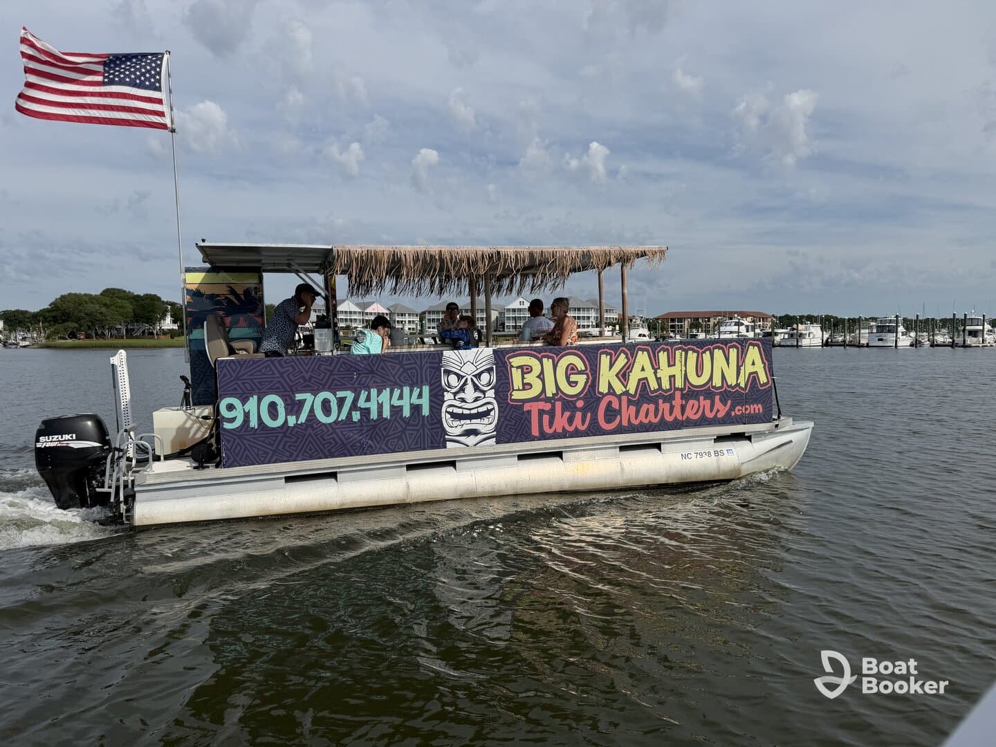 A lively tiki charter boat, 'Big Kahuna,' cruises through calm waters with guests enjoying the ride — perfect for fun outings and family adventures.
