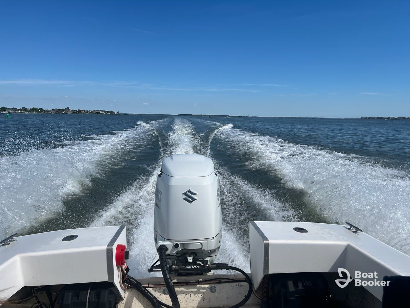 A dynamic view from the back of a speedboat cruising through calm waters, showcasing the powerful engine and the wake created behind it.