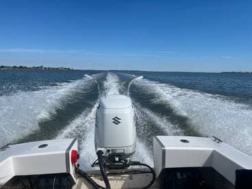 A dynamic view from the back of a speedboat cruising through calm waters, showcasing the powerful engine and the wake created behind it.