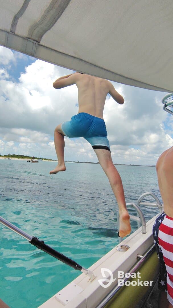 A young boy leaps off the side of a boat into the clear turquoise waters, capturing the thrill of summer fun and on-water adventures.