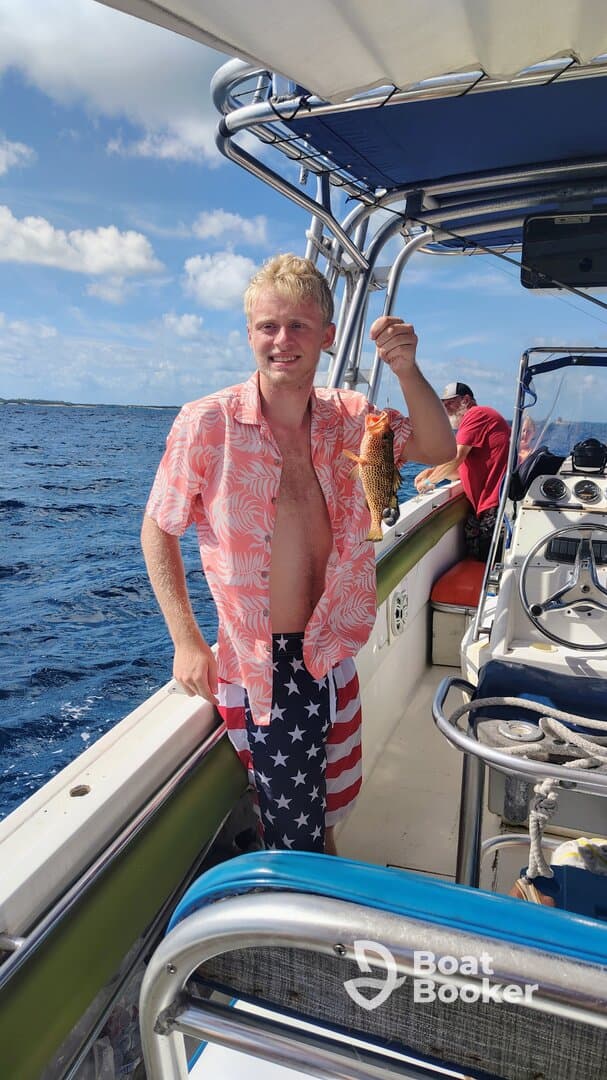 A young man proudly displays his catch while fishing on a boat, showcasing the excitement of a successful day on the water.
