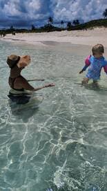 A joyful moment captured as a woman interacts with a child in the shallow waters of a beautiful beach, perfect for family fun and memorable summer days.