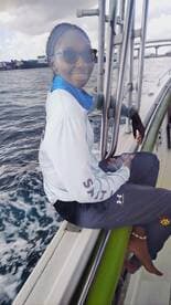 A woman enjoys her time on a boat, capturing the moment with her phone while surrounded by the beautiful ocean scenery.