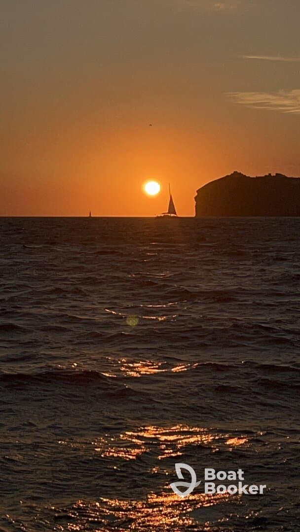 A serene sunset view featuring a sailboat silhouetted against the vibrant horizon, perfect for capturing the beauty of evening on the water.
