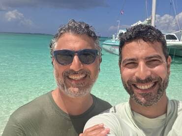 Two friends enjoy a sunny day at the beach, capturing a joyful moment with a beautiful turquoise backdrop — perfect for memorable vacation snapshots.