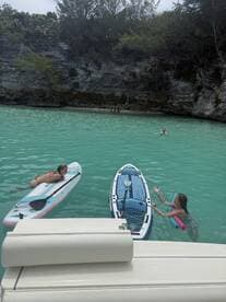 Two children enjoy paddleboarding and swimming in crystal-clear turquoise waters, creating a perfect summer adventure on the water.