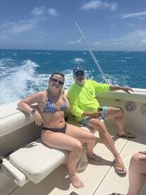 A couple relaxes on the deck of a boat, enjoying the sunny ocean views — perfect for a day of fun on the water.
