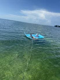 Two children enjoy a fun day on a floating mat in clear waters, perfect for summer adventures and family outings.