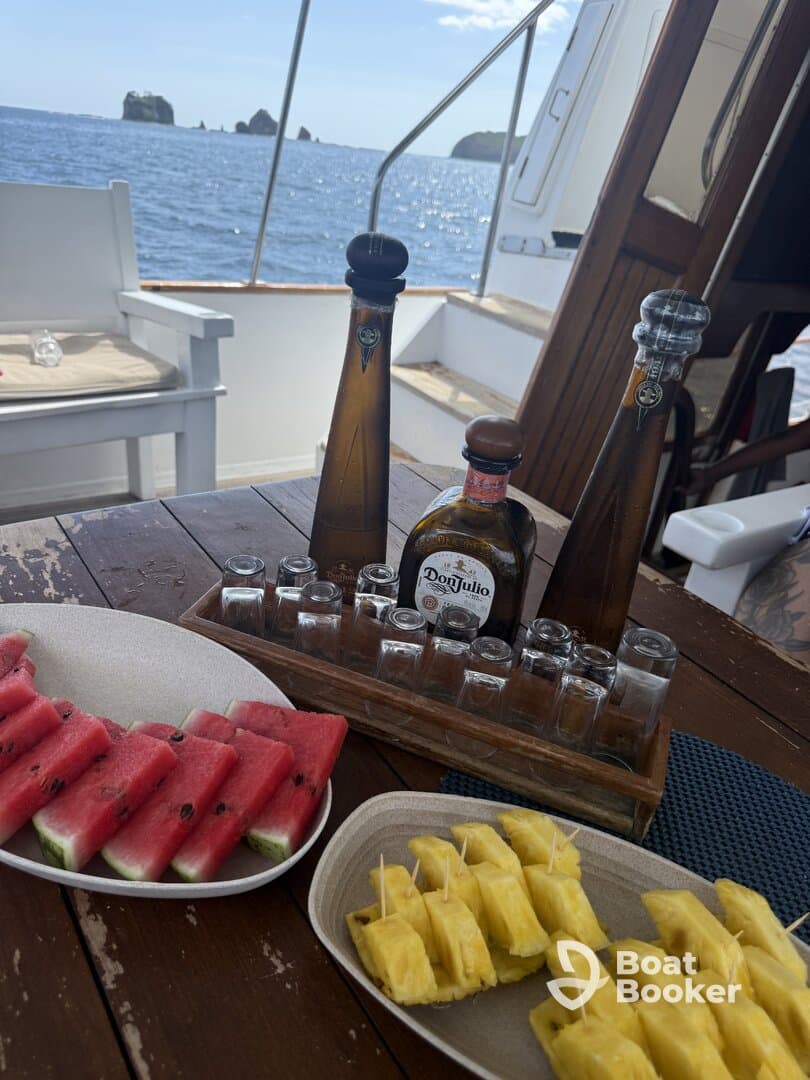 A beautifully arranged spread of fresh watermelon and pineapple alongside tequila bottles, perfect for enjoying on a boat. Ideal for a relaxing day at sea.