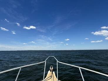 A stunning view from the bow of a boat, showcasing the expansive water and clear blue skies — perfect for a day out on the water.