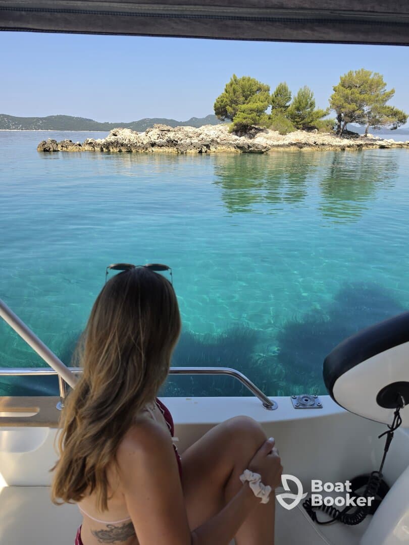 A woman enjoys a serene view of a picturesque island from the deck of a boat, perfect for relaxation and scenic escapes on the water.