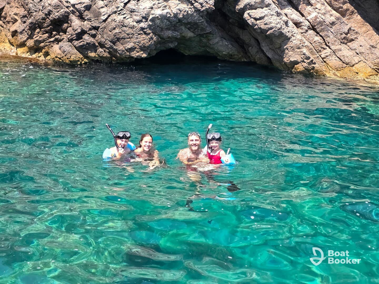 A joyful family enjoys snorkeling in crystal-clear waters, surrounded by stunning rock formations — a perfect adventure for creating unforgettable memories.