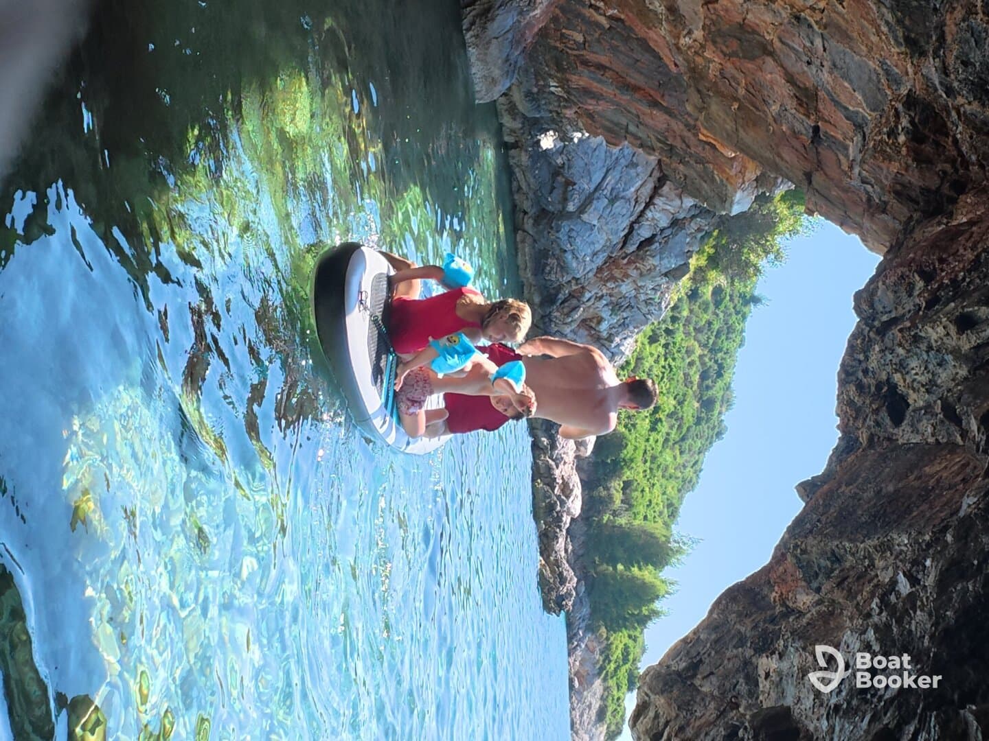 A family enjoys paddleboarding in a serene cove, surrounded by stunning rock formations and clear waters — a perfect adventure for creating lasting memories.
