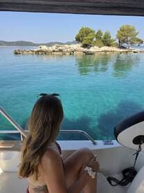 A woman enjoys a serene view of a picturesque island from the deck of a boat, perfect for relaxation and scenic escapes on the water.