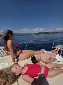 A family enjoys a sunny day on the boat, relaxing and sunbathing under clear blue skies — a perfect summer getaway on the water.